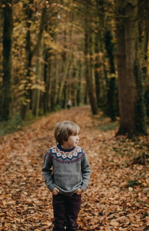Boy walking on a trail in the woods.